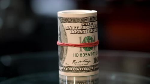 Money roll of hundred dollar bills on table represents business success and financial grow