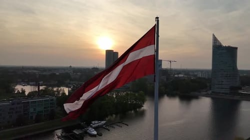 Aerial View of Latvian Flag Waving on Flagpole in Capital City Riga at Sunset Daugava River Slow
