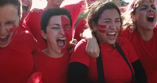 Enthusiastic sports fans cheering, wearing red