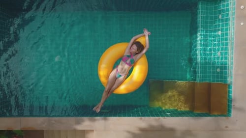 Woman Relaxing on Yellow Inflatable Ring in Green Water Pool