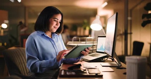 Woman uses tablet in office at night