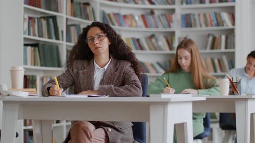 Gruppe junger kluger Studentinnen, die Notizen in Kopierbücher schreiben, im College-Klassenzimmer kostenlos