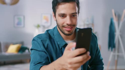 Smiling Man Using Smartphone in Bright Living Room