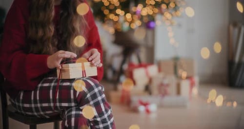 Woman Opening Christmas Gift in Cozy Home Setting