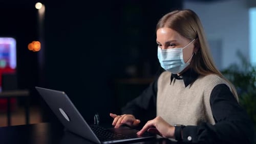Woman with Mask Works on Laptop in Office