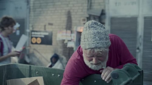 Elderly Homeless Man Searching through Trash Bin on Street
