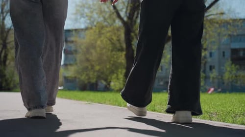 People Walking Along City Sidewalk Chalked Shadows and Textured Street Surface Early Spring Evening