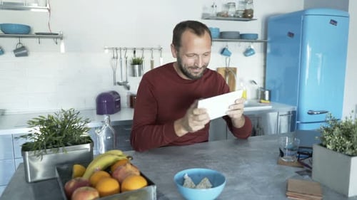 Man Uses Tablet in Bright Modern Kitchen