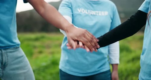 Volunteers Joining Hands in Green Field