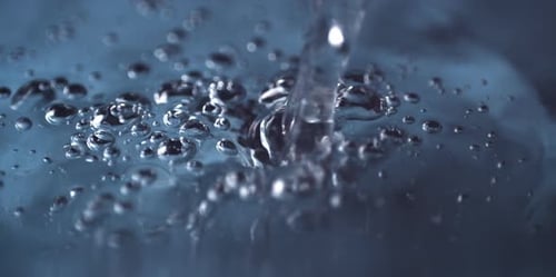 Water Pouring Creates Bubbles on Blue Background