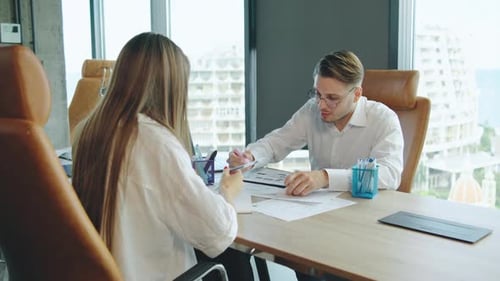 Professional Discussion Occurs in Modern Office Between Two People While Reviewing Documents in a