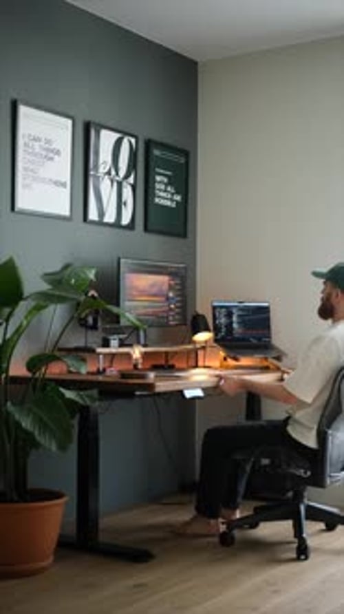 Un jeune homme en casquette s'assoit pour travailler à son bureau à la maison