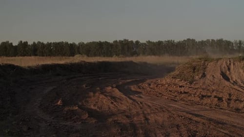 Racer Rides Motorcycle Along Dirt Track with Sharp Turn at Dusk