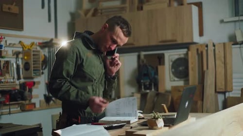 Man Talks on Phone in Carpentry Workshop