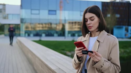 Woman Using Phone and Credit Card Outdoors