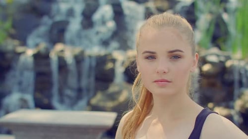 Blonde Woman Posing in Park. Young Woman Portrait Near Waterfall. Close Up