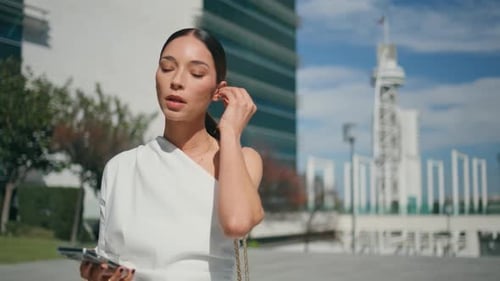 Attractive Woman Putting Earbuds in Ears Starting Phone Call at Street Close Up