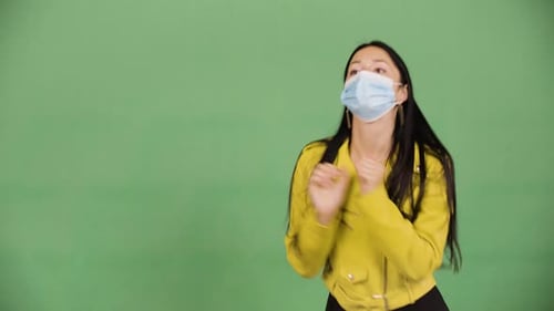 Eine junge kaukasische Frau mit Gesichtsmaske tanzt, nimmt die Maske ab und wirft sie weg. Green Screen