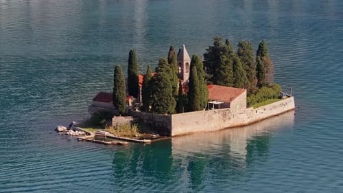 Aerial drone view of the small natural island of Saint George, featuring a stone monastery surrounde