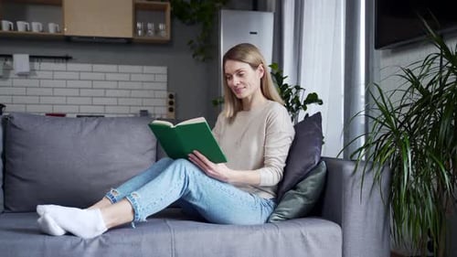 Woman Reading a Book on Couch at Home