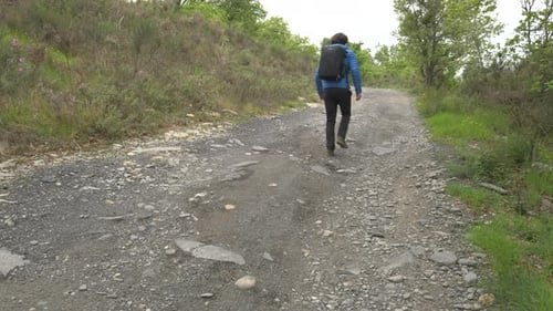 Young man, backpacker hiking in mountain road, adventure travel concept, hiker doing trekking
