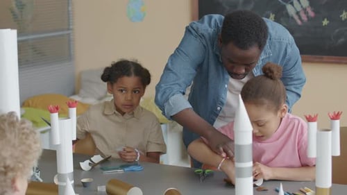 School Teacher Helping Little Girls with Making Paper Craft