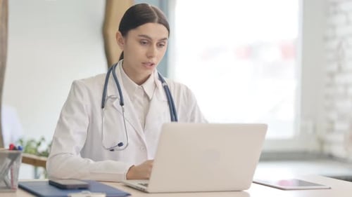 Online Video Chat by Young Female Doctor on Laptop in Clinic