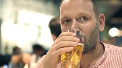 Handsome young man enjoys a refreshing beer at a cafe on a late night