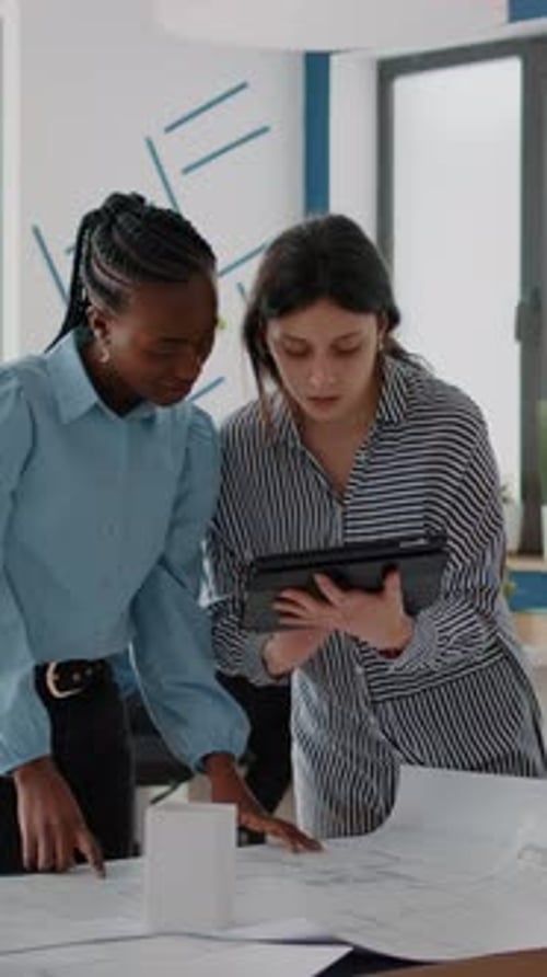 Two Women Collaborate on Design in Office