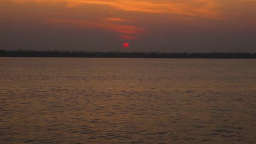 Wide-angle shot of sea landscape with a red sun on the sky during the sunset.