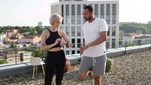 Fit Couple Exercising on City Rooftop