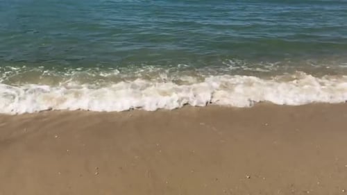 Foamy sea wave washing into shore - close up during the day