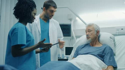 In the Hospital, Senior Man Lying in the Bed, Talks with Doctor and Nurse who Diagnose Him Using Ta