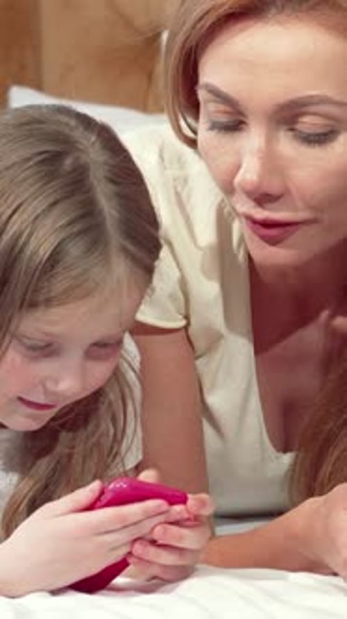 Child and Woman Play on Phone in Bed