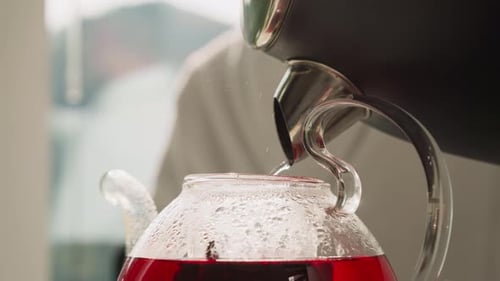 Pouring Hot Water into Glass Teapot