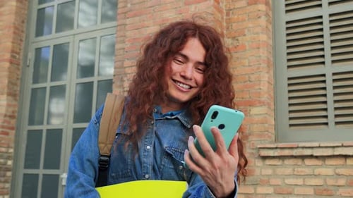 Happy Young University Student Using Her Smartphone for Messaging in Social Media or Watching Funny