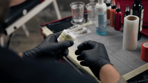 Tattoo Artist Preparing Tattoo Machine With Orange Bandage