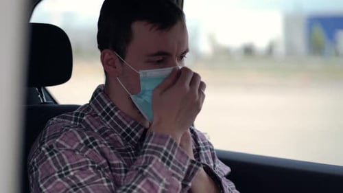 Man Puts on Protective Face Mask in Car