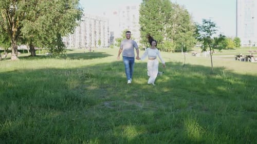 Happy Wife and Husband Running and Enjoying the Summer in the Park