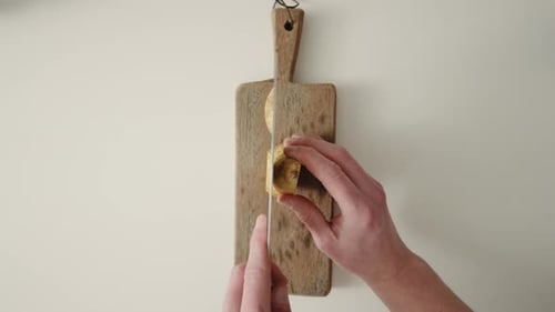 Hands cutting ripe pear in slices on a wooden cutting board with sharp knife. Top Shot 4K