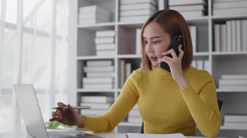 Businesswoman is talking to clients and colleague on the phone and working on laptop in office