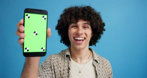 Man, phone and green screen in studio with face, smile or excited with mockup space by blue