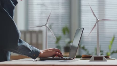 Renewable Energy Engineer Working on Laptop at Desk in the Office