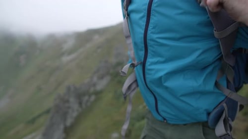 Un homme en randonnée enfile un sac à dos et attache sa ceinture en gros plan