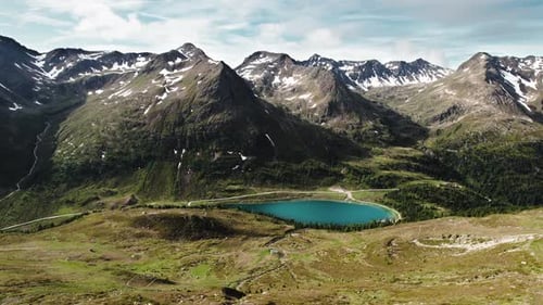 Turquoise mountain lake surrounded by partly snow-covered alpine terrain, on the border between Ital