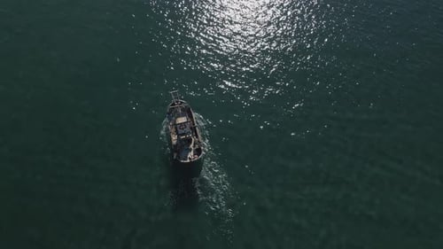 Aerial view of fishing boat on shallow water, moving closer into the horizon