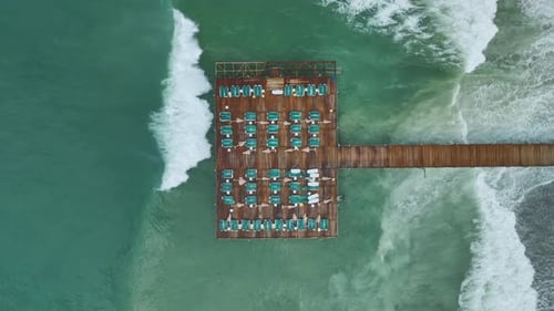 Vídeo aéreo de um píer de madeira que se estende da costa até o amplo oceano azul aberto