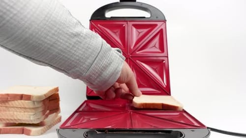 Preparing Bread in a Red Sandwich Press