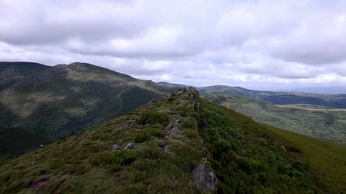 Aerial drone footage following a rocky peak trail in a beautiful mountain range.