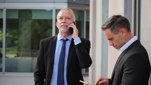 Businessmen Discuss Technology Outdoors on Tablet and Phone